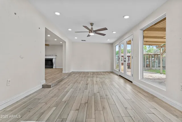 a view of a big room with wooden floor a ceiling fan and windows