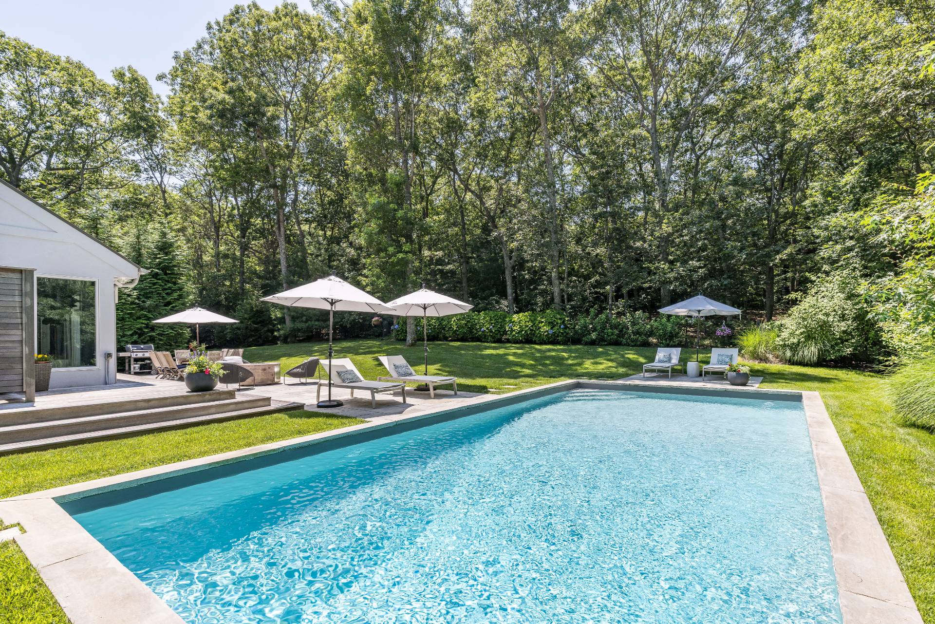 27 Landfall Road East Hampton, NY 11937 - Photo 21 of 24 a view of a swimming pool with lawn chairs under an umbrella