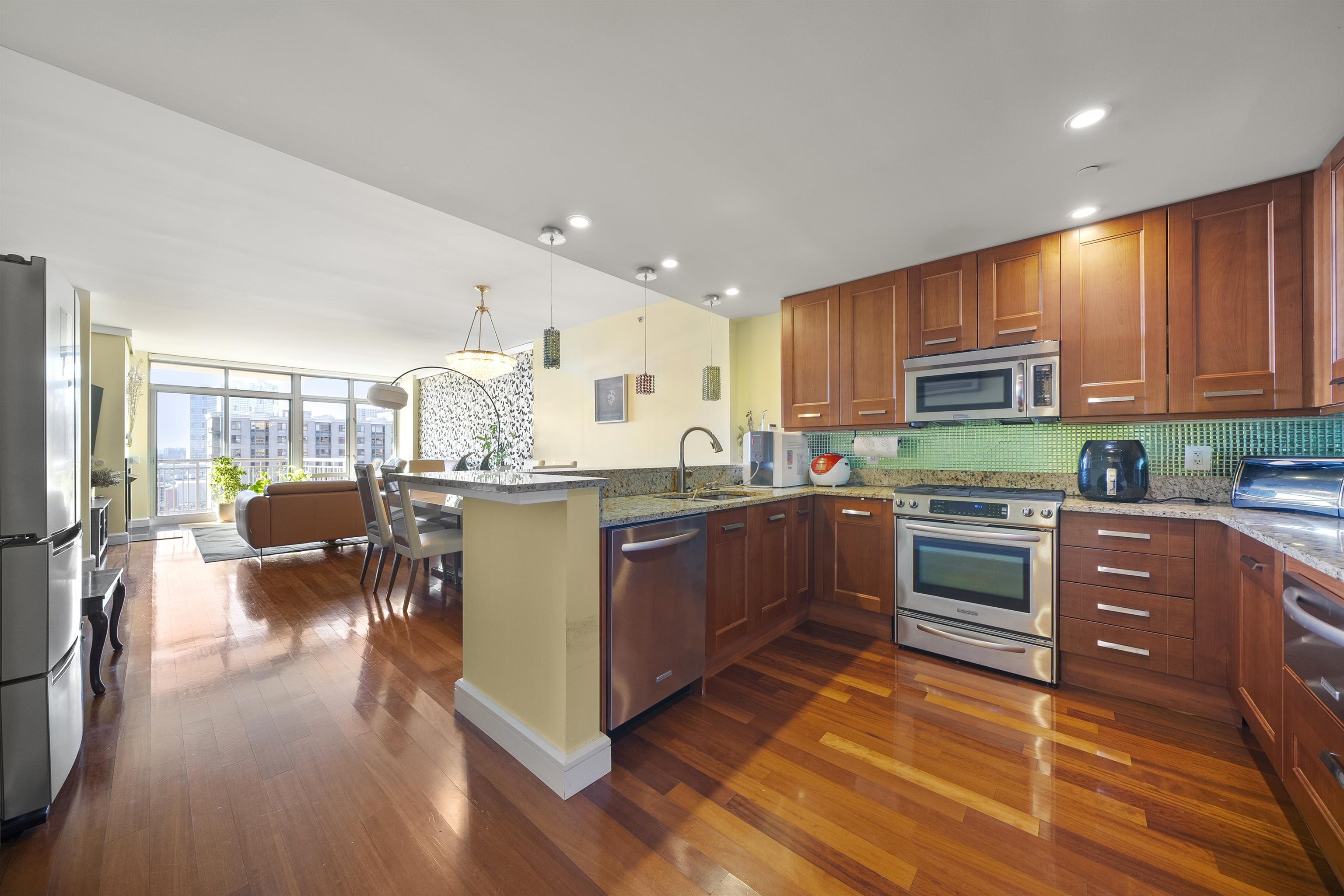 8100 River Road, Unit 1011 North Bergen, NJ 07047 - Photo 5 of 35 a kitchen with stainless steel appliances kitchen island granite countertop wooden floors and a view of living room