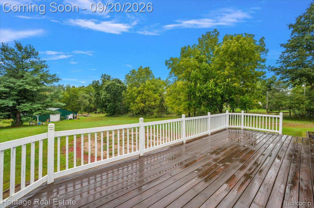 3337 Le Valley Road Columbiaville, MI 48421 - Photo 6 of 57 Expansive wooden deck with white railings, surrounded by mature trees and a green lawn