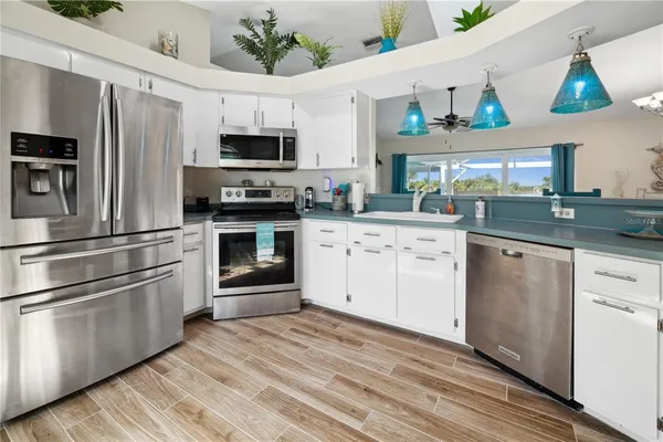 a kitchen with stainless steel appliances granite countertop a refrigerator oven a sink dishwasher and white cabinets with wooden floor
