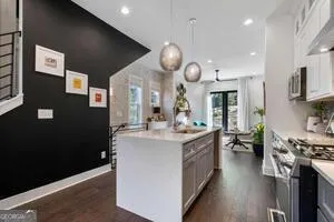 a kitchen with stainless steel appliances granite countertop a stove a sink a refrigerator and a dining table with wooden floor