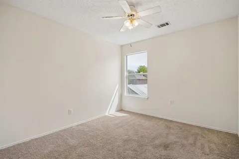 an empty room with windows and fan