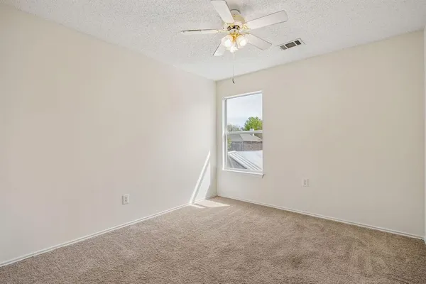 an empty room with windows and fan