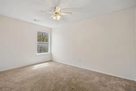 an empty room with windows and fan