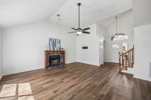 a view of a livingroom with a fireplace a ceiling fan and wooden floor