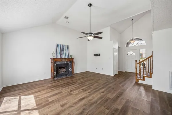 a view of a livingroom with a fireplace a ceiling fan and wooden floor
