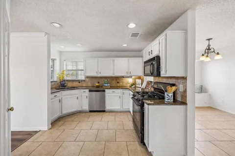 a kitchen with a sink a stove top oven a refrigerator and cabinets