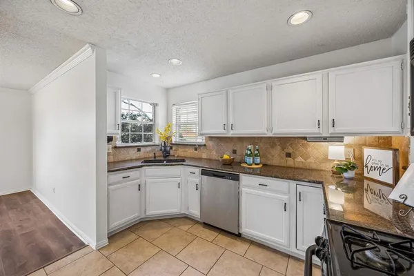 a kitchen with granite countertop white cabinets sink and stainless steel appliances
