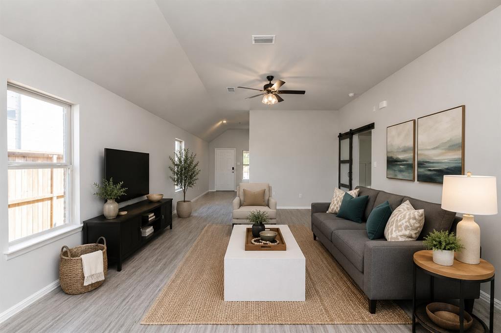 3344 Duncan Way Corinth, TX 76210 - Photo 5 of 38 Expansive living area featuring vaulted ceilings, wood-finish flooring, a contemporary ceiling fan with integrated lighting, and a barn door entry