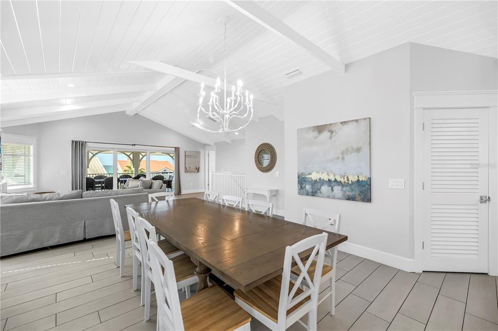 316 Beach Road Sarasota, FL 34242 - Photo 75 of 98 a dining room with wooden floor a chandelier a wooden table and chairs