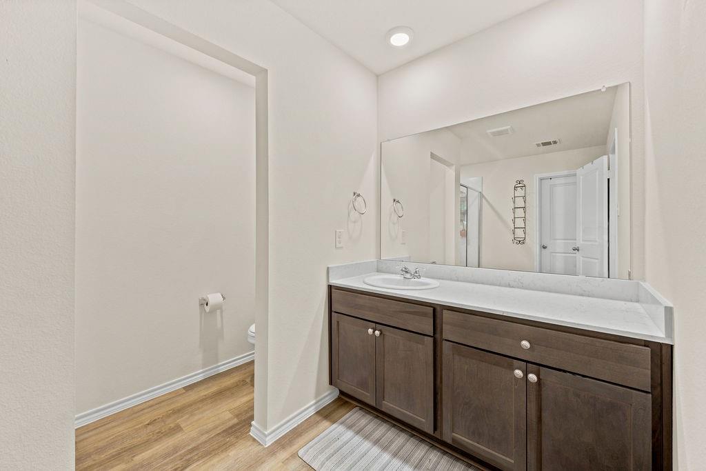 822 Ramble Road Lavon, TX 75166 - Photo 26 of 35 Bathroom vanity featuring a single sink, light-toned countertop, and dark wood-finish cabinetry