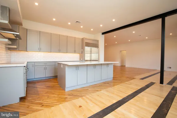 a large kitchen with stainless steel appliances a large counter top a stove and a sink