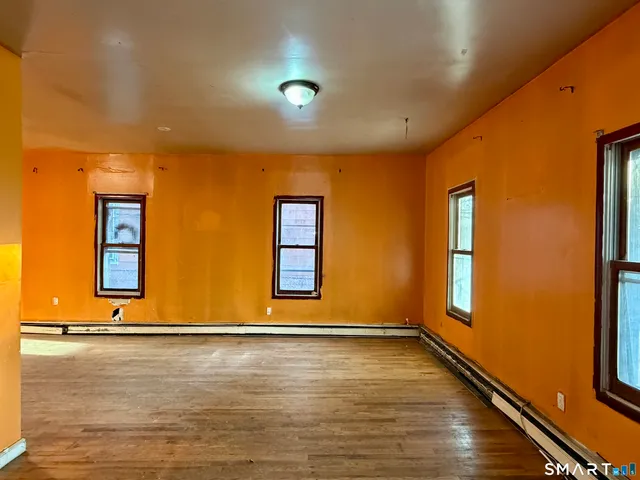 an empty room with wooden floor and natural light