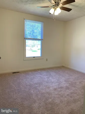 an empty room with a window and a fan