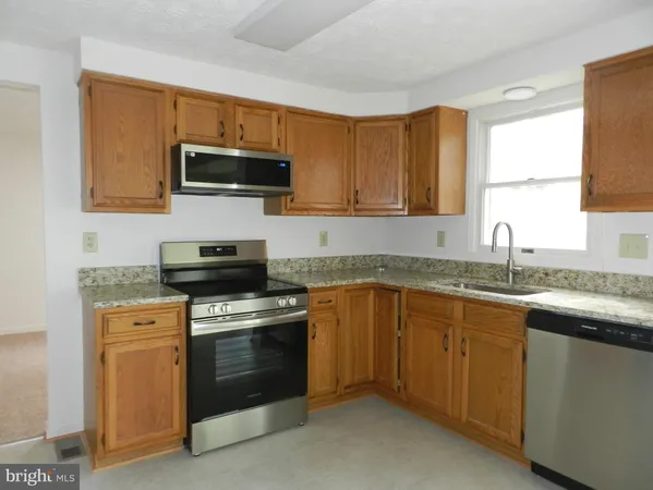 a kitchen with granite countertop a sink dishwasher stove and microwave with wooden floor