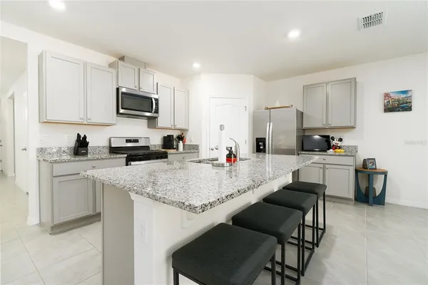 a kitchen with stainless steel appliances granite countertop a stove a sink a refrigerator and a refrigerator