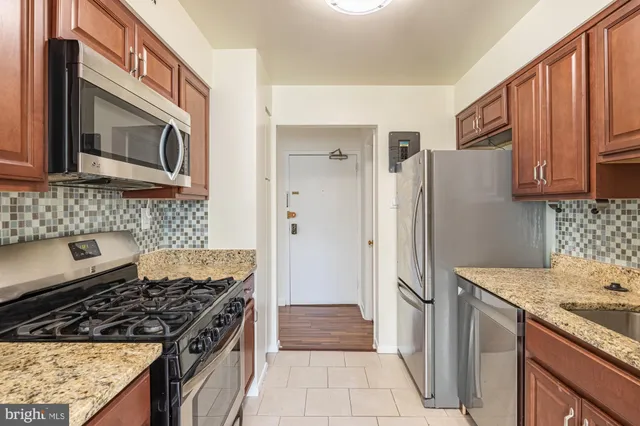 a kitchen with stainless steel appliances granite countertop a refrigerator and a stove top oven