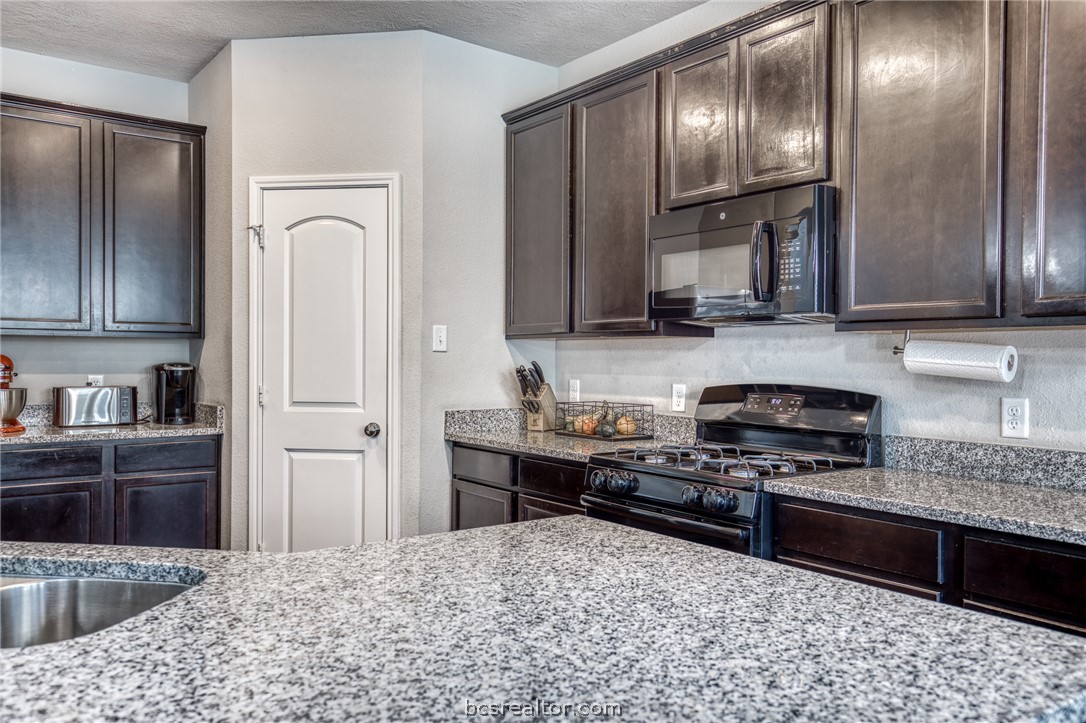 1827 Basin Trail Brenham, TX 77833 - Photo 8 of 38 a kitchen with granite countertop stainless steel appliances and wooden cabinets
