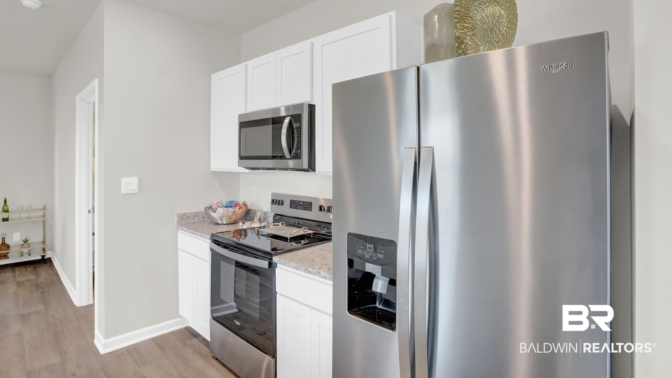 13330 Shea Circle Foley, AL 36535 - Photo 6 of 15 Modern kitchen featuring stainless steel appliances, white cabinetry, speckled countertops, and wood-finish flooring