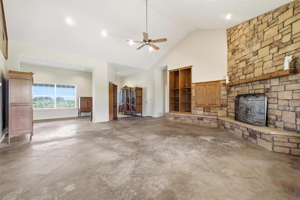 12190 Bell Road Pilot Point, TX 76258 - Photo 12 of 39 Spacious room featuring vaulted ceilings, a stone fireplace with a wood mantel, built-in shelving, and concrete flooring