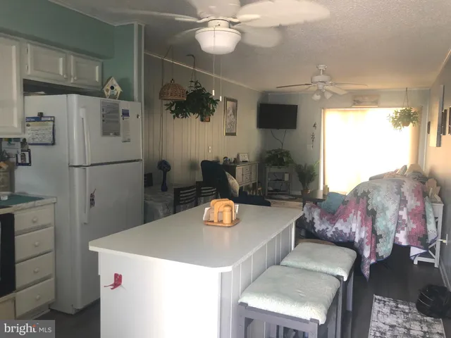 a kitchen with stainless steel appliances kitchen island granite countertop a refrigerator a stove and a sink with couches