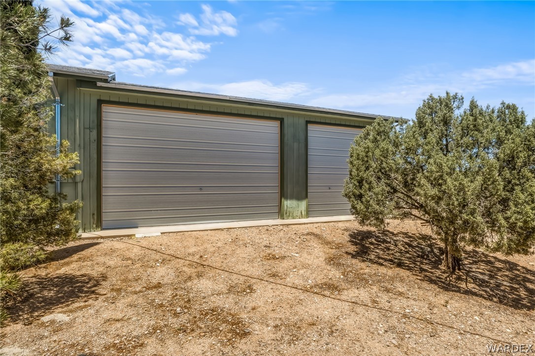 2401 North Stephan Road Kingman, AZ 86401 - Photo 16 of 92 Metal-sided outbuilding featuring two roll-up garage doors of varying sizes, set on a concrete foundation