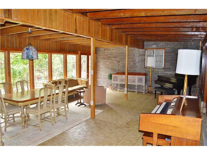 Family Room. Another view through the large and open family room toward the interior exposed stone wall,  exposed wood ceilings lead to the wall of windows and French door that lead to the back patio
