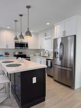 a kitchen with stainless steel appliances granite countertop a sink a stove a refrigerator and island with wooden floor
