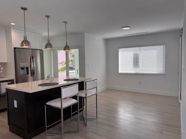 a kitchen with a table chairs refrigerator and wooden floor