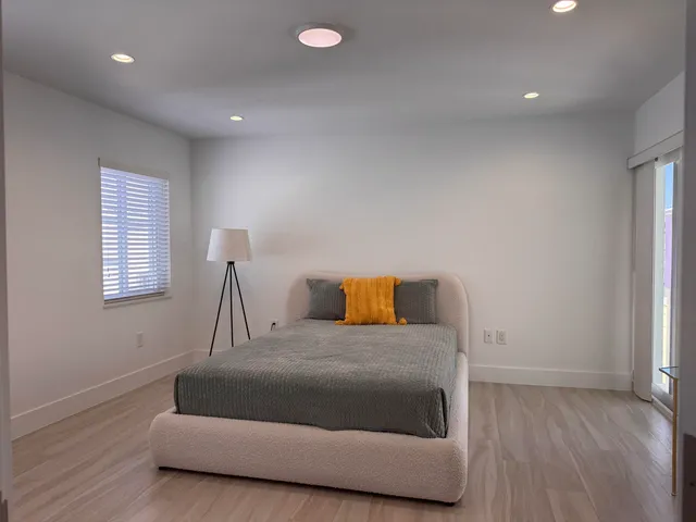 a spacious bedroom with a bed and wooden floor