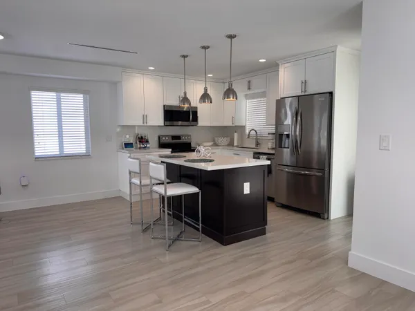 a kitchen with stainless steel appliances granite countertop a sink a stove a refrigerator and island with wooden floor