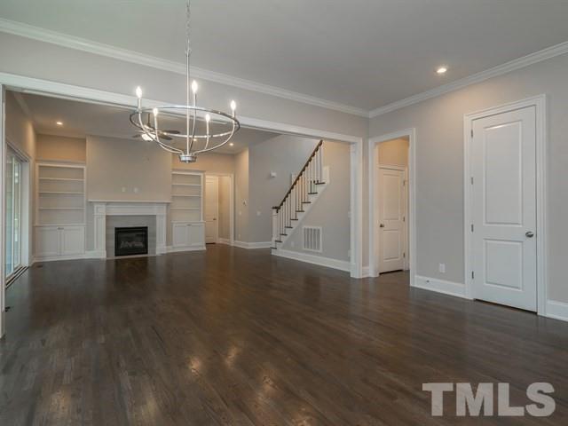 1425 Starry Night Court Raleigh, NC 27613 - Photo 13 of 33 an empty room with wooden floor fireplace and staircase