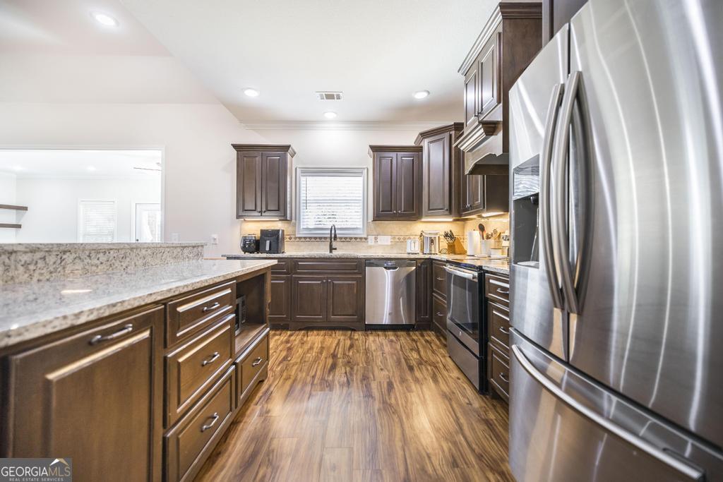219 Rowland Circle Byron, GA 31008 - Photo 14 of 47 a kitchen with stainless steel appliances granite countertop a refrigerator a sink dishwasher a stove and white countertops with wooden floor