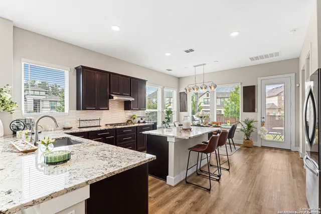 a kitchen with sink stove refrigerator dining table and chairs