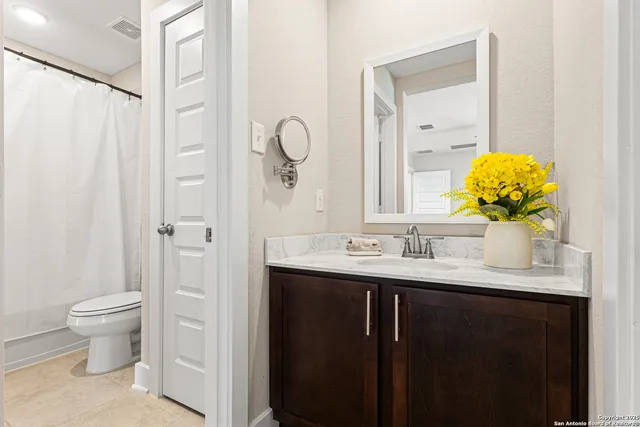 a bathroom with a granite countertop sink a toilet and a mirror