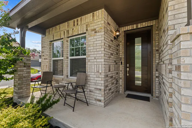 a balcony with table and chairs and potted plants