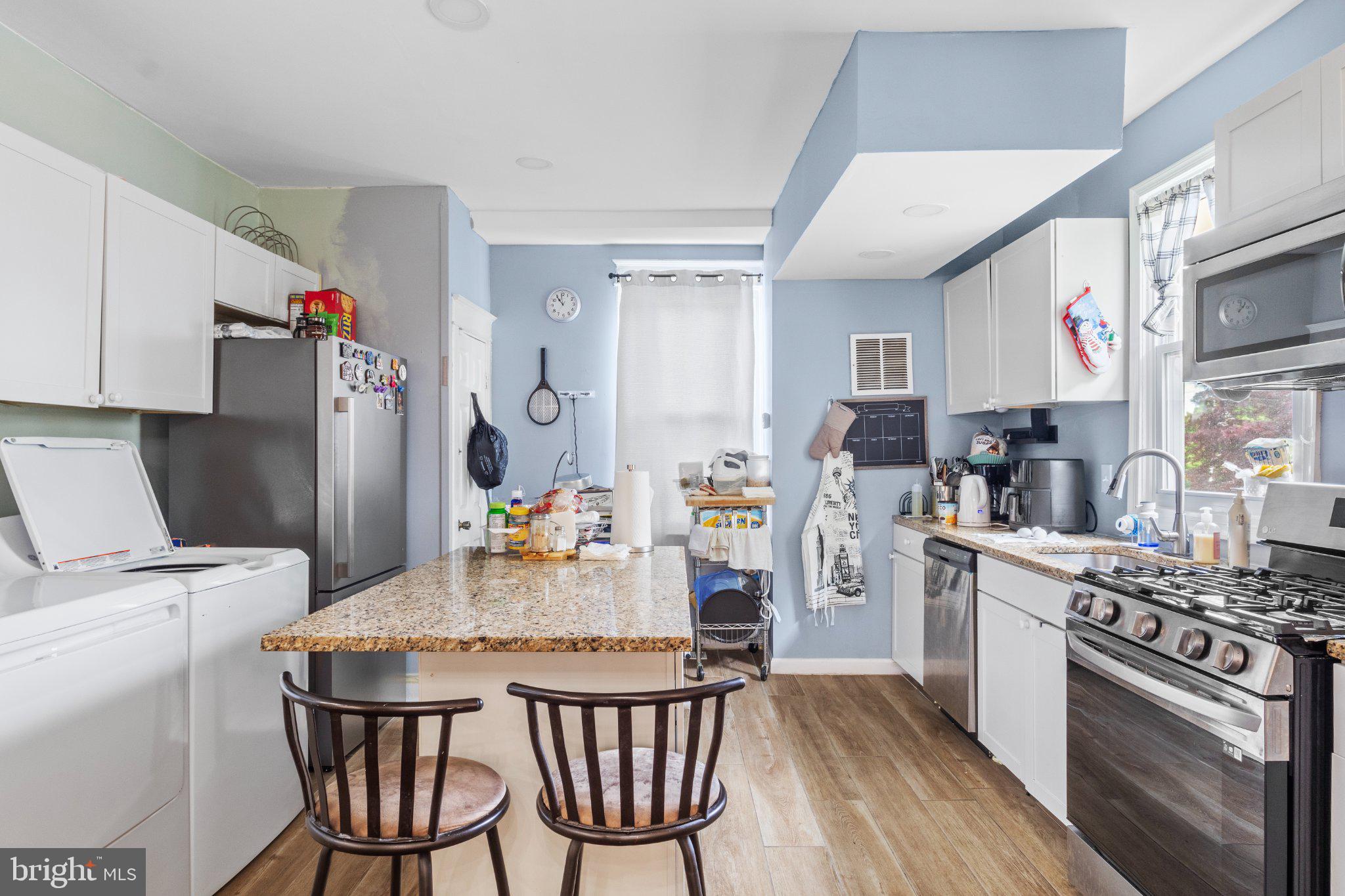 130 West Edgevale Road Baltimore, MD 21225 - Photo 15 of 37 a kitchen with stainless steel appliances kitchen island granite countertop a refrigerator a stove a sink dishwasher and white cabinets with wooden floor