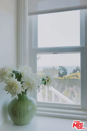 a vase of flowers sitting on a table with window