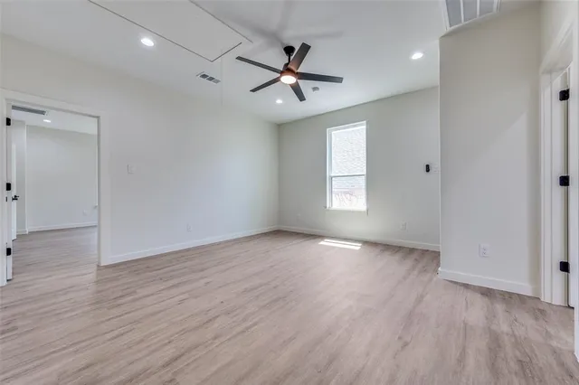 an empty room with wooden floor a ceiling fan and windows