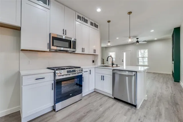 a kitchen with stainless steel appliances white cabinets a sink and a stove