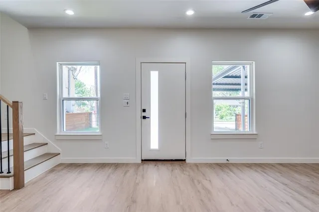 an empty room with wooden floor and windows