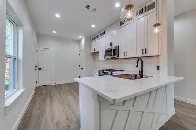a kitchen with a sink a microwave a stove and cabinets