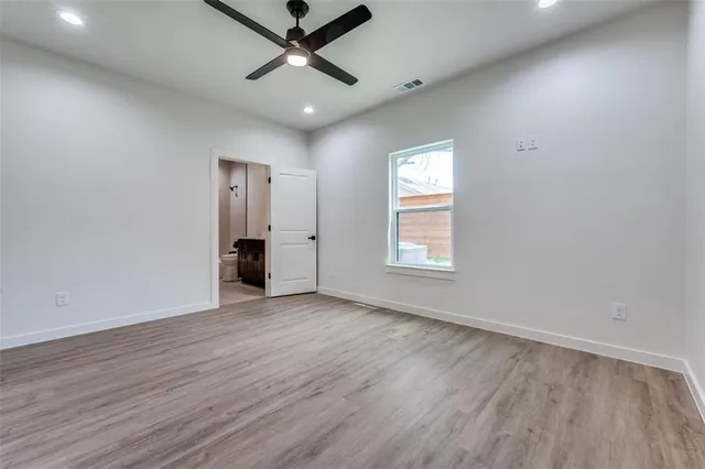 an empty room with wooden floor chandelier fan and windows