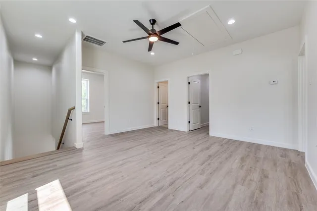 an empty room with wooden floor and a ceiling fan