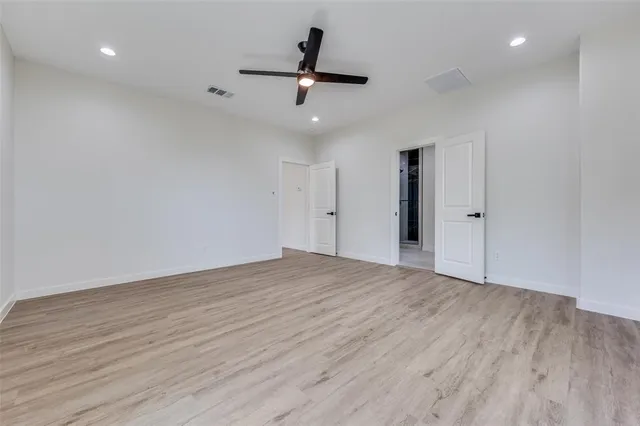 an empty room with wooden floor and ceiling fan