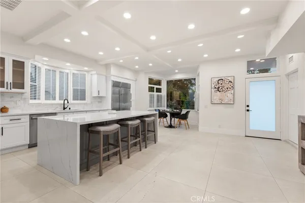 a large white kitchen with cabinets chairs and a sink