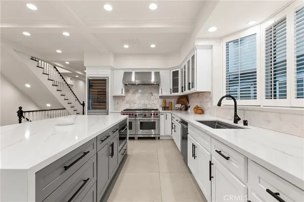 a large white kitchen with stainless steel appliances lots of counter space and a sink