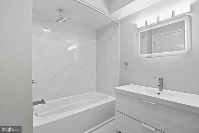 a bathroom with a tub a sink and mirror