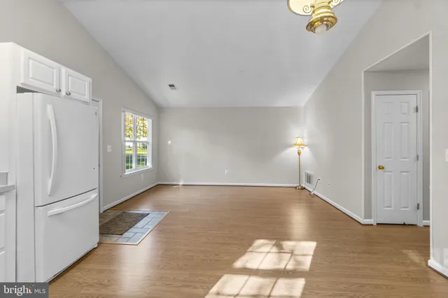 a view of an empty room with window and wooden floor